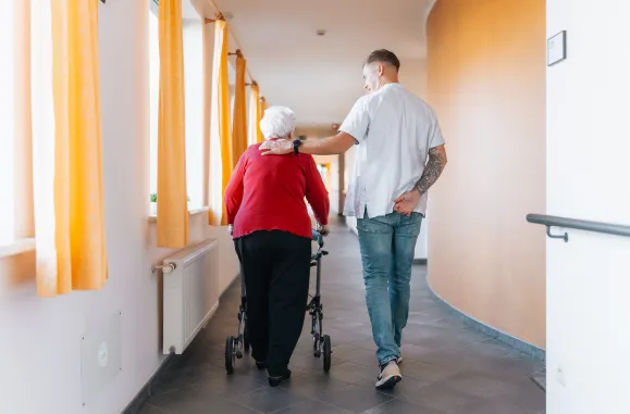 Verpleegkundige en patiënt, wandelend in de gang
